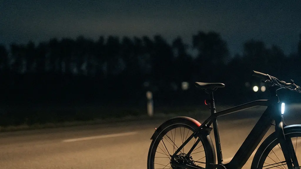 A fast e-bike parked on a dim roadside at night with its integrated headlight off, while distant traffic lights blur in the background.