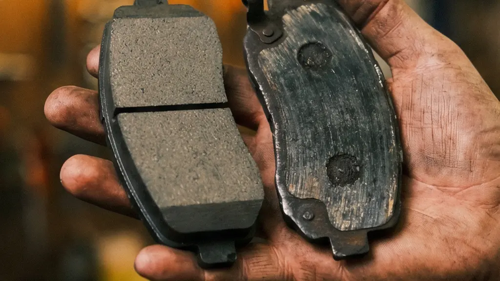Close-up detail shot of a heavily worn e-bike metallic brake pad next to a brand new pad, showing the dramatic difference in friction material thickness.